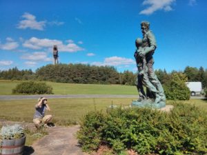 nathan kneeling to photograph a statue with the ski jump in the background